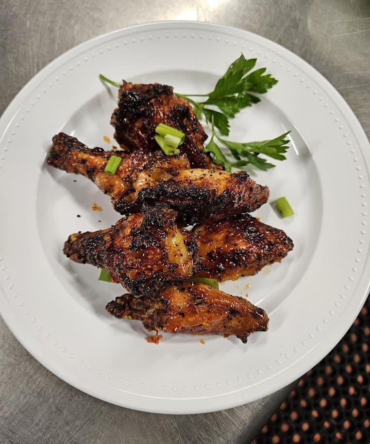 Glazed BBQ chicken wings plated with herbs