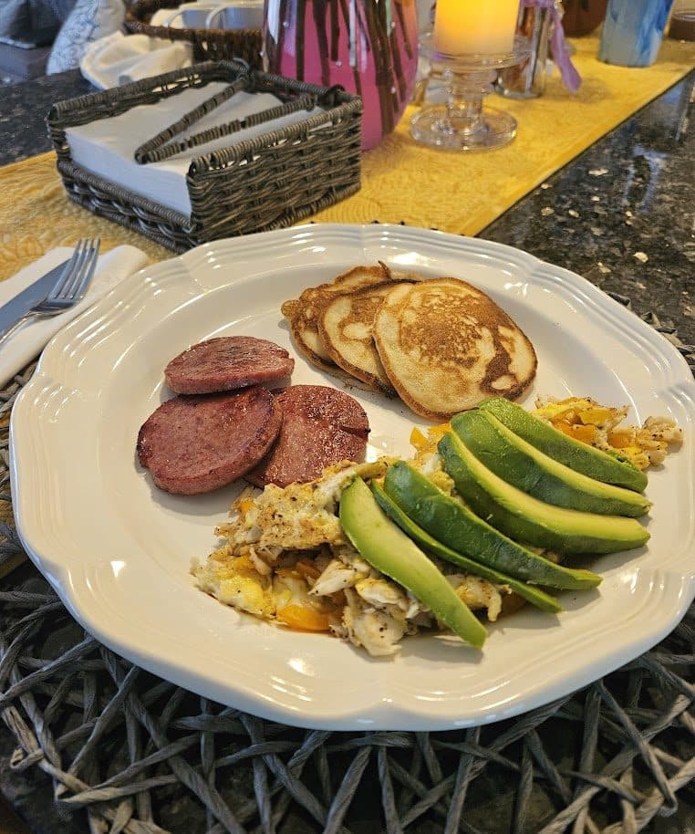 Dominican breakfast plate with pancakes, salami, eggs, and avocado