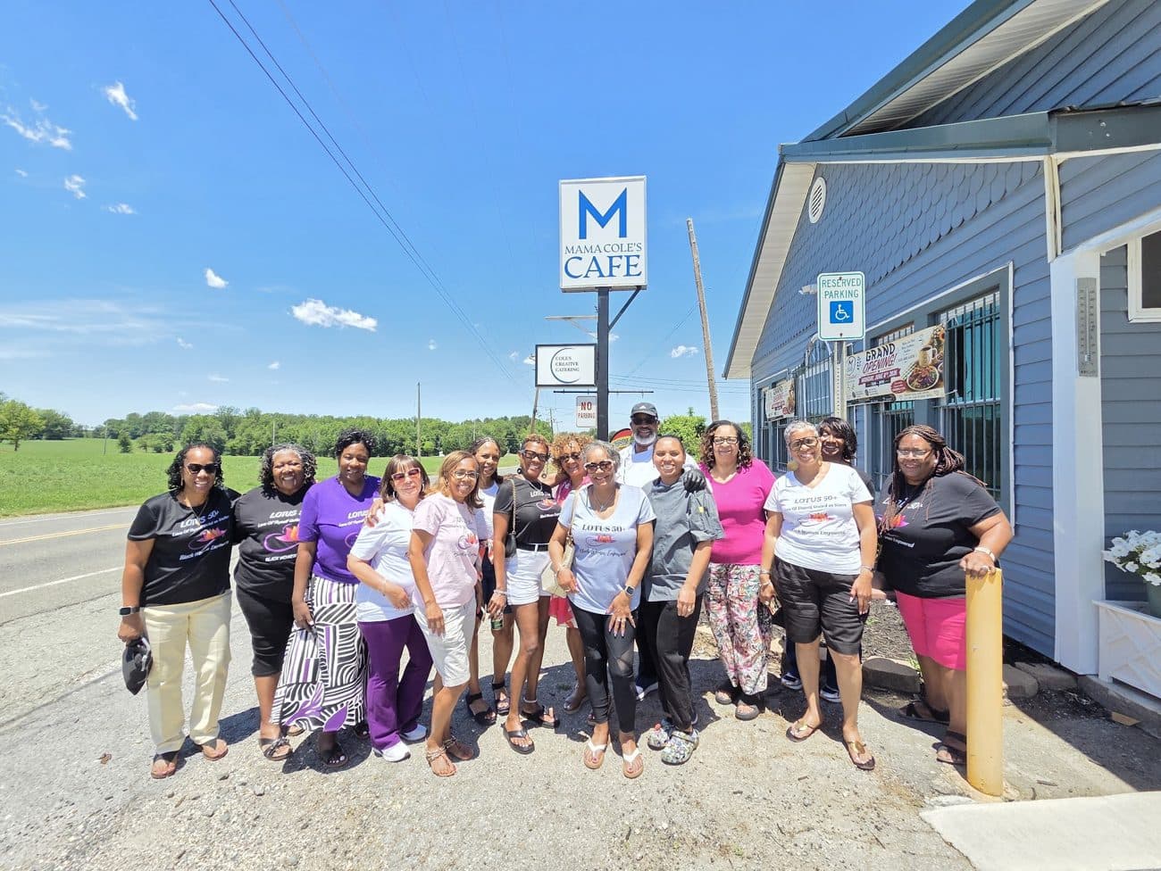 The Mama Cole's family and team in front of the cafe sign